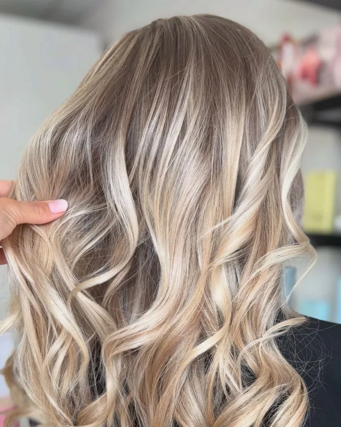 Balayage blond bouclé réalisé chez Entre Filles, salon de coiffure à Saint-Pol-sur-Mer